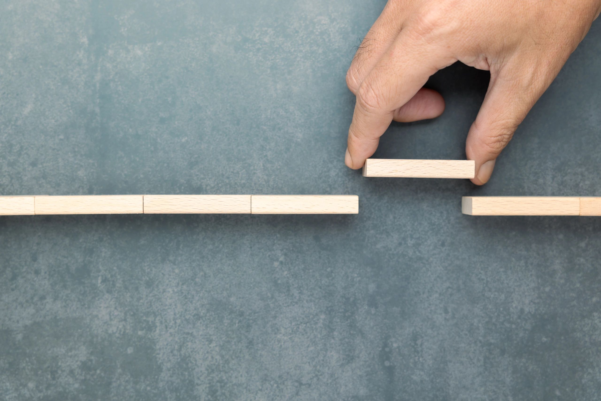 Hand placing a wooden block to bridge the gap in a path