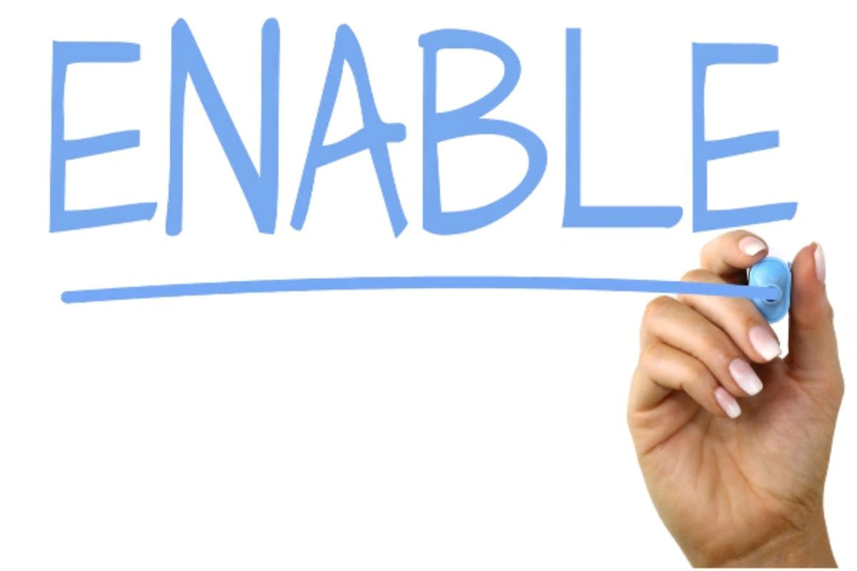 Hand writing the word ENABLE in blue marker