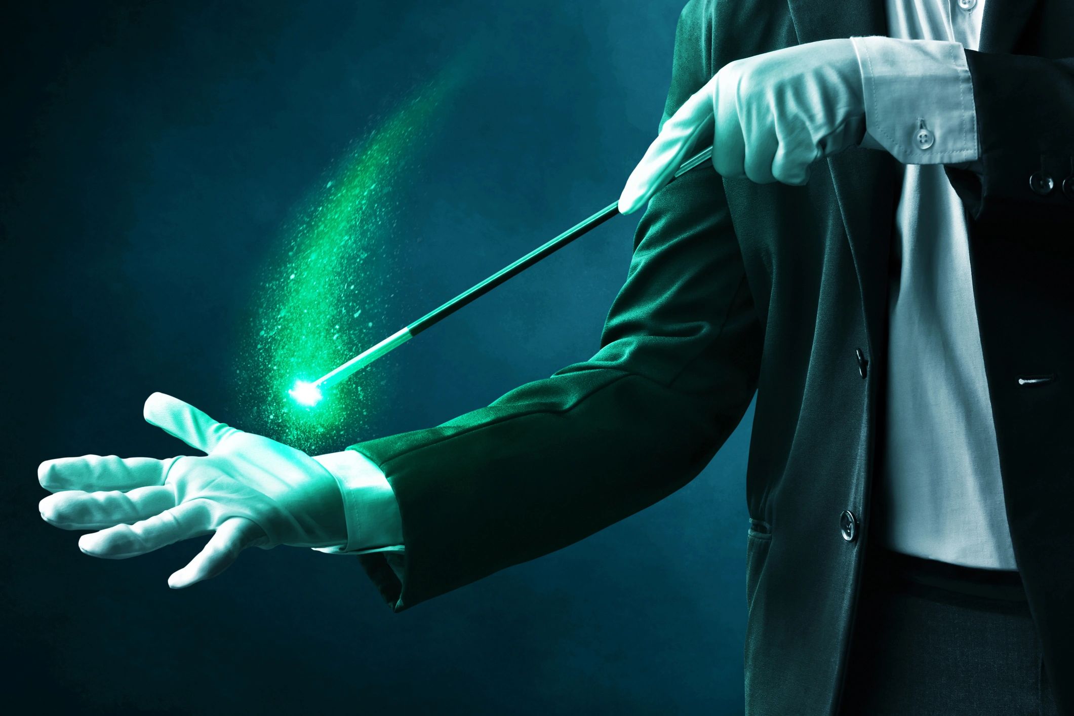 Magician in a suit and white gloves holding a magic wand